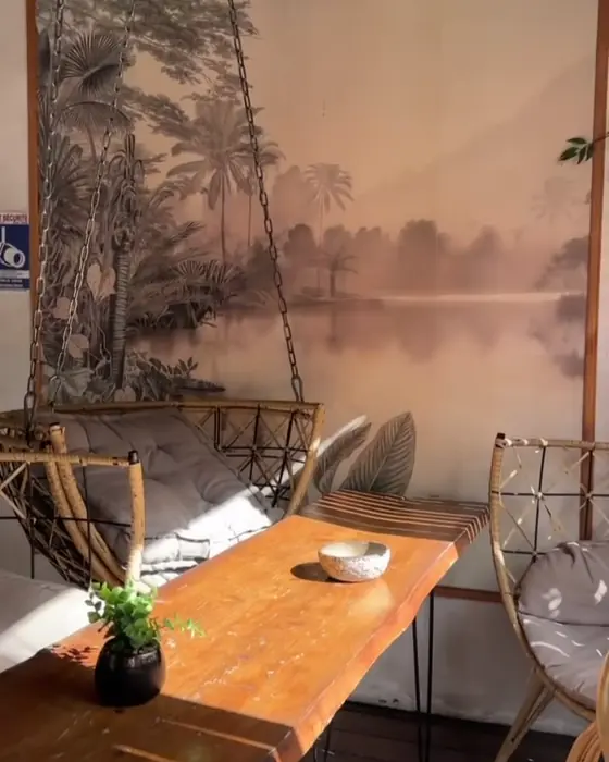 L'entrée : papier peint tropical, balancelle en rotin et table en bois brut