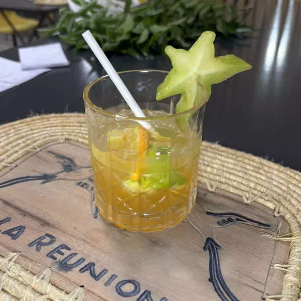 Cocktail ambré décoré d'une carambole, sur un set en paille gravé La Réunion
