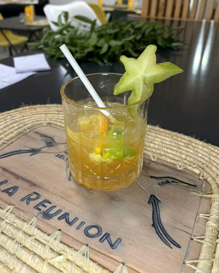 Cocktail ambré décoré d'une carambole, sur un set en paille gravé La Réunion