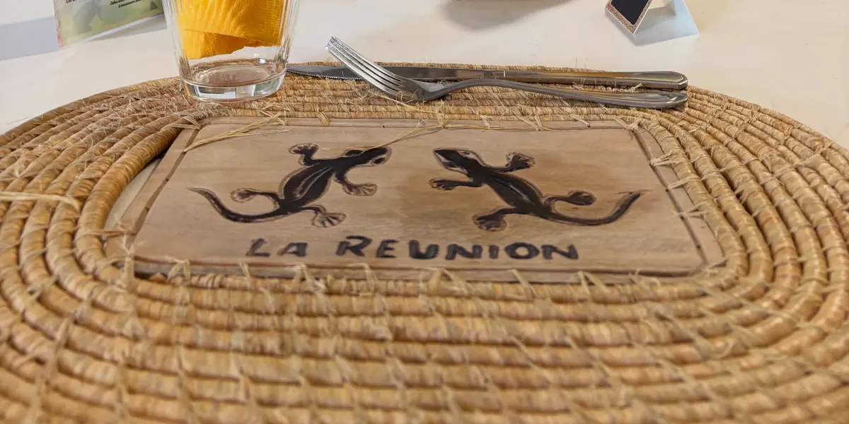 Un set de table en paille tressée, sa plaque en bois gravée de deux margouillats et de « La Réunion »
